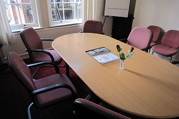 A conference table with red chairs around it